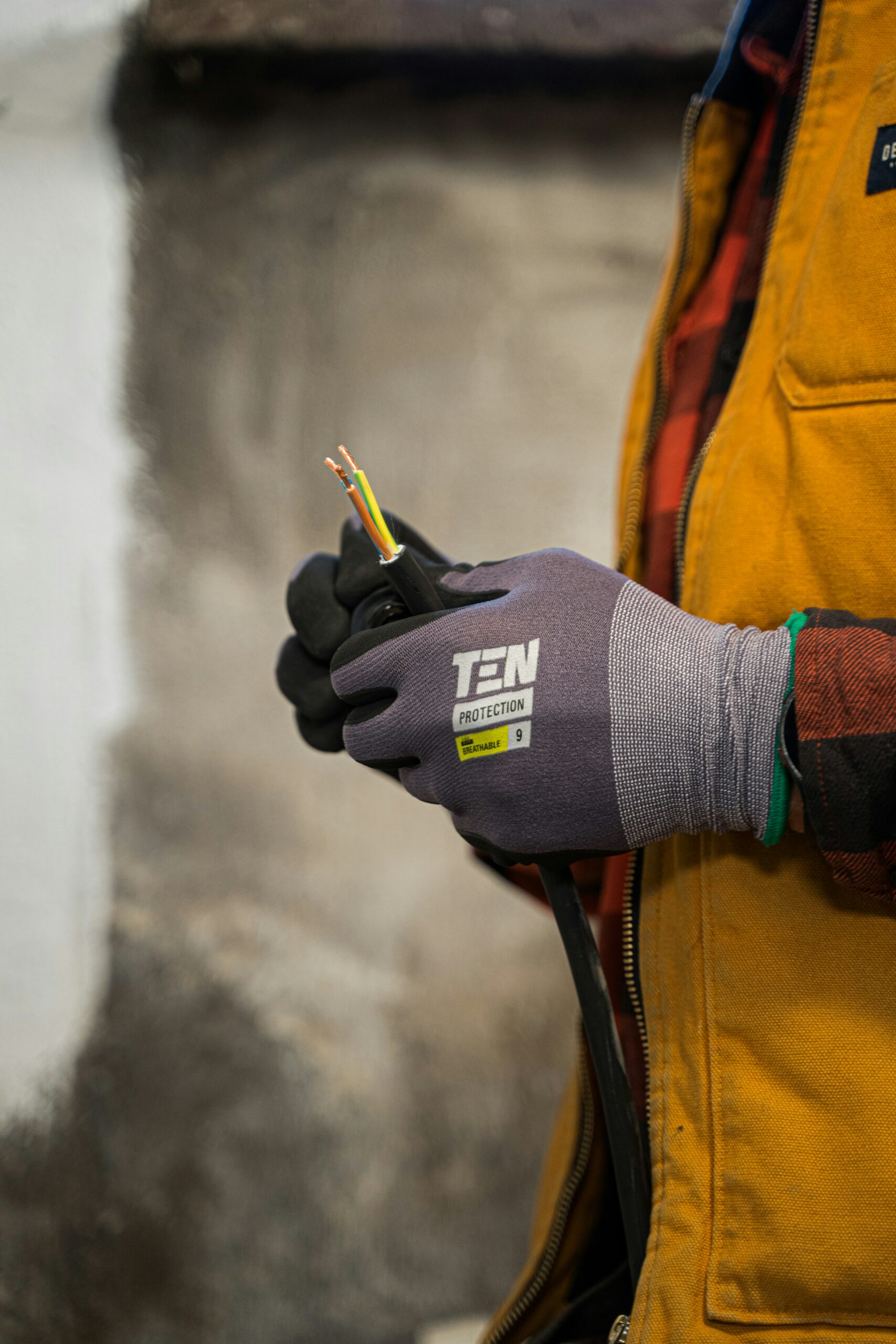 Manipulation sécurisée d'un câble électrique Homme avec des gants tenant un câble électrique dénudé
