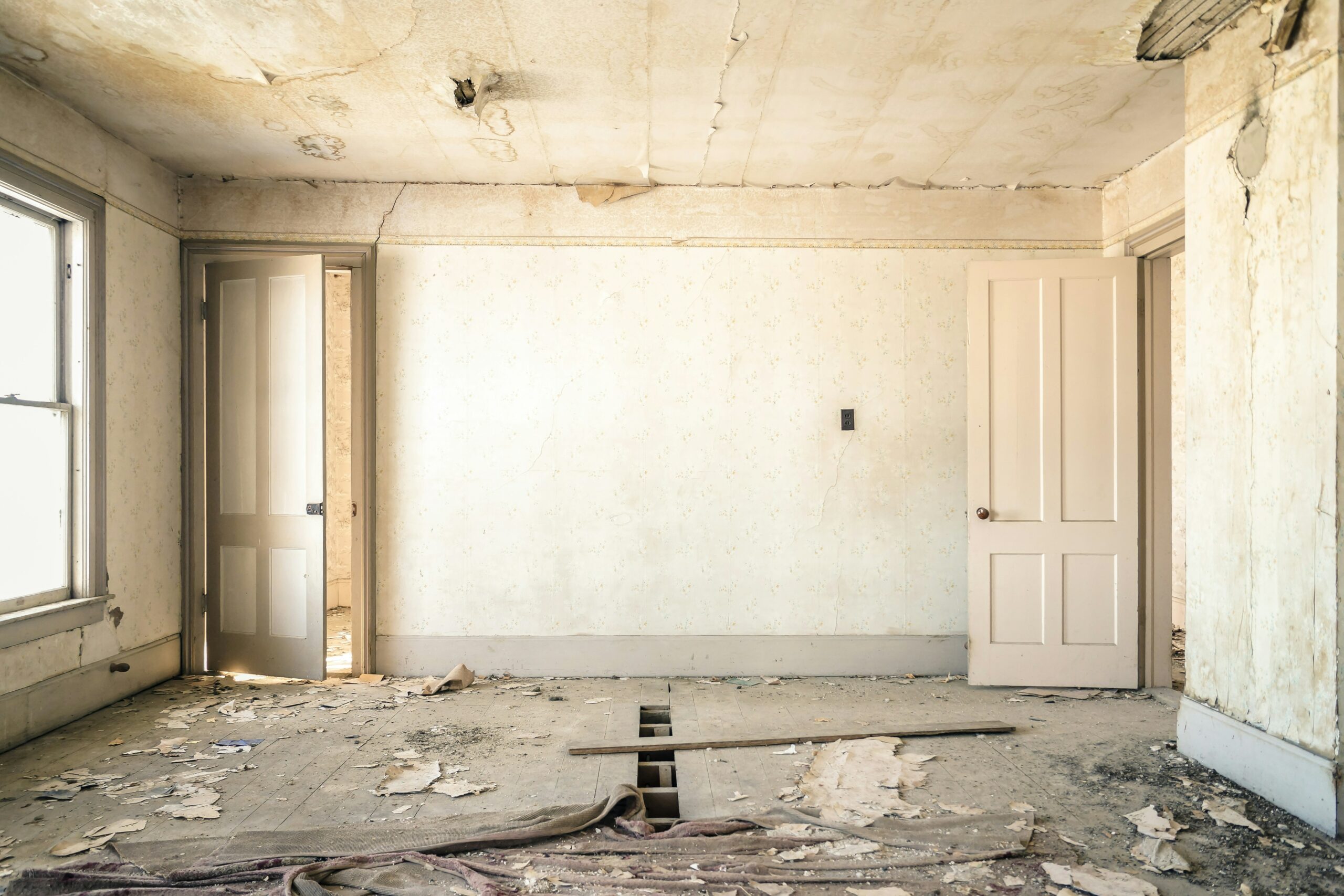 Pièce abandonnée en état de délabrement Pièce abandonnée avec portes entrouvertes et parquet délabré